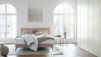 Rosa Design Polsterbett in einem hellen Schlafzimmer.