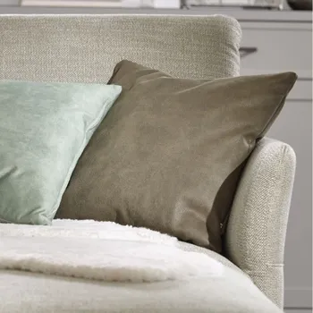 Hellgrüner Longchair eines Ecksofas, das mit Kissen und Decke dekoriert ist.