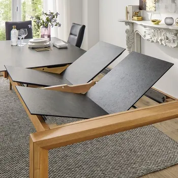 Esstisch mit schwarzer Tischplatte an dem zwei weitere Tischplatten zur Verlängerung angebracht werden.