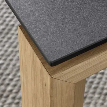 Ecke eines Esstisches mit Schwarzer Tischplatte und Massivholzgestell.