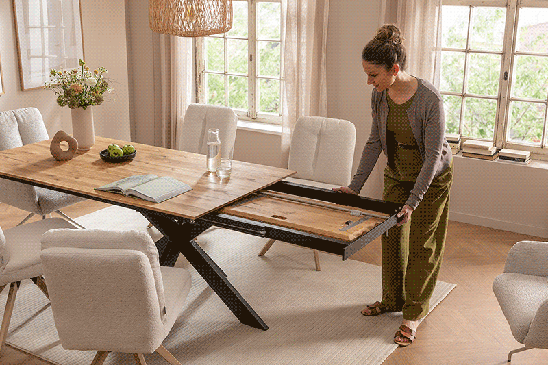 Butterfly-Auszug eines Massivholz-Esstischs, der von einer Frau im Esszimmer verwendet wird.
