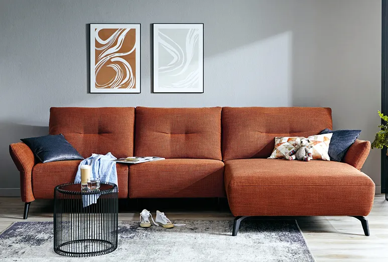 Komfortables Sofa in rostbrauch mit Couchtisch vor grauer Wand, hohe Sitzhöhe für Senioren