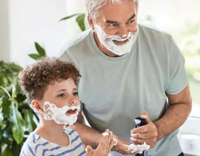 Großvater, Opa mit Jungen im Bad beim Rasieren mit Rasierschaum im Gesicht