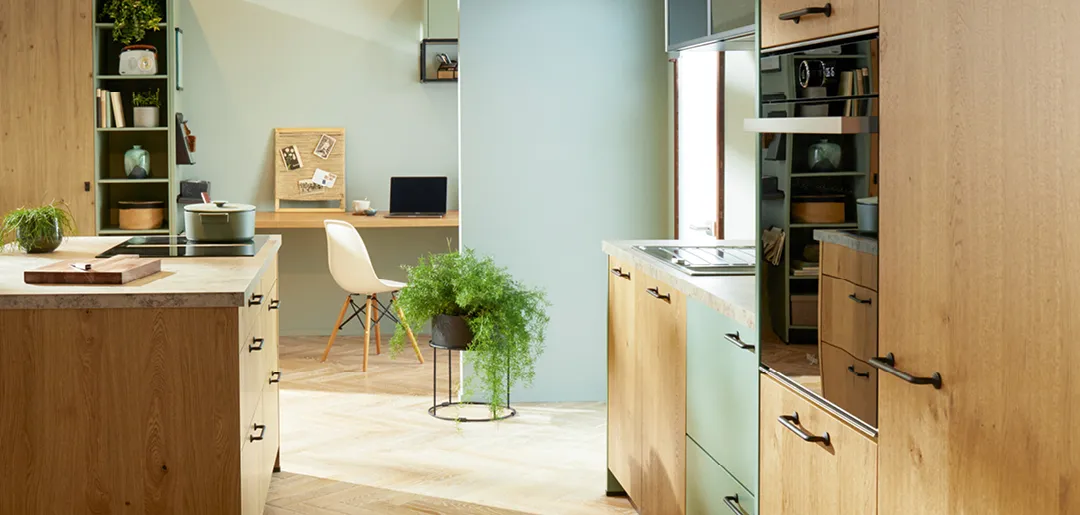 Gemütliche Wohnküche auf Holzparkett im Holzlook mit mit mintgrünen Fronten und Kochinsel