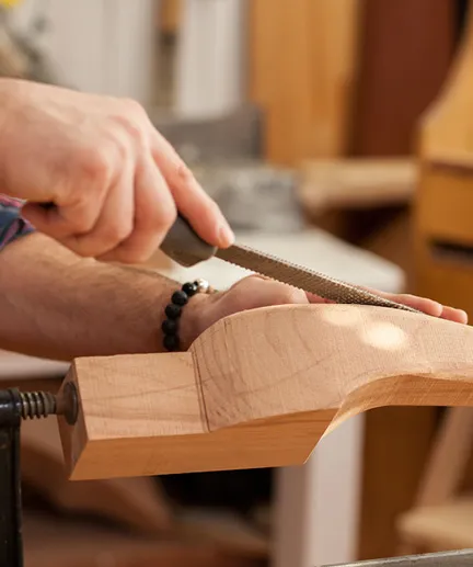 Holzbein eines Möbelstückes wird mit einer Raspel bearbeitet.