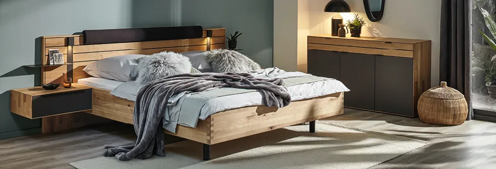 Schickes Holzbett mit anthrazitfarbenen Akzenten in Schlafzimmer