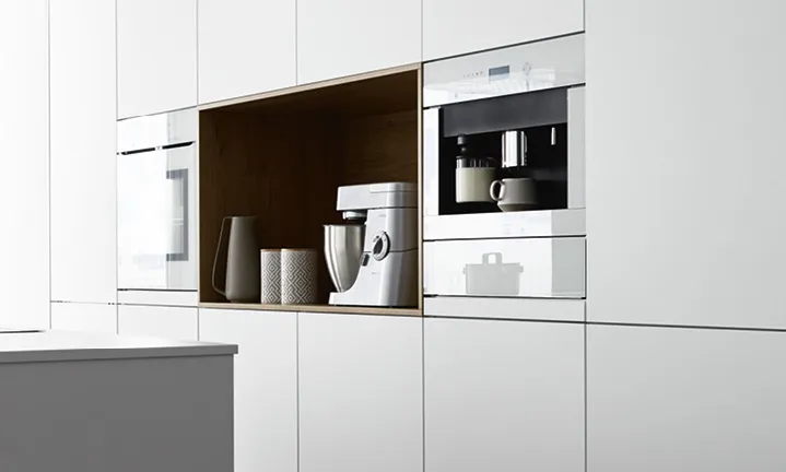 Küchenwand mit Ofen Kaffeemaschine und Rührgerät.