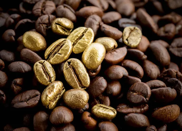 Goldene Kaffebohnen zwischen normalen Kaffeebohnen