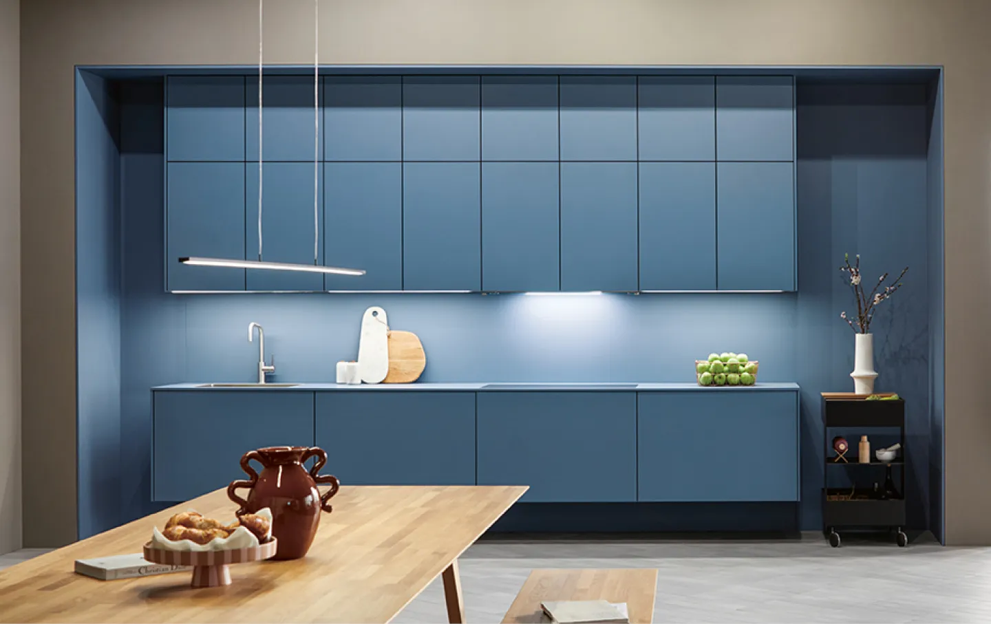 Blaue in die Wand eingelassene Kuechenzeile in minimalistischem Stil vor Esstisch