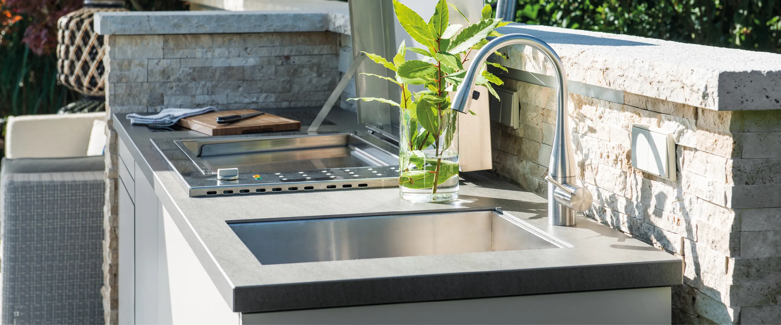 Arbeitsflaeche einer stylischen OCQ-Outdoorkueche vor Steinmauer