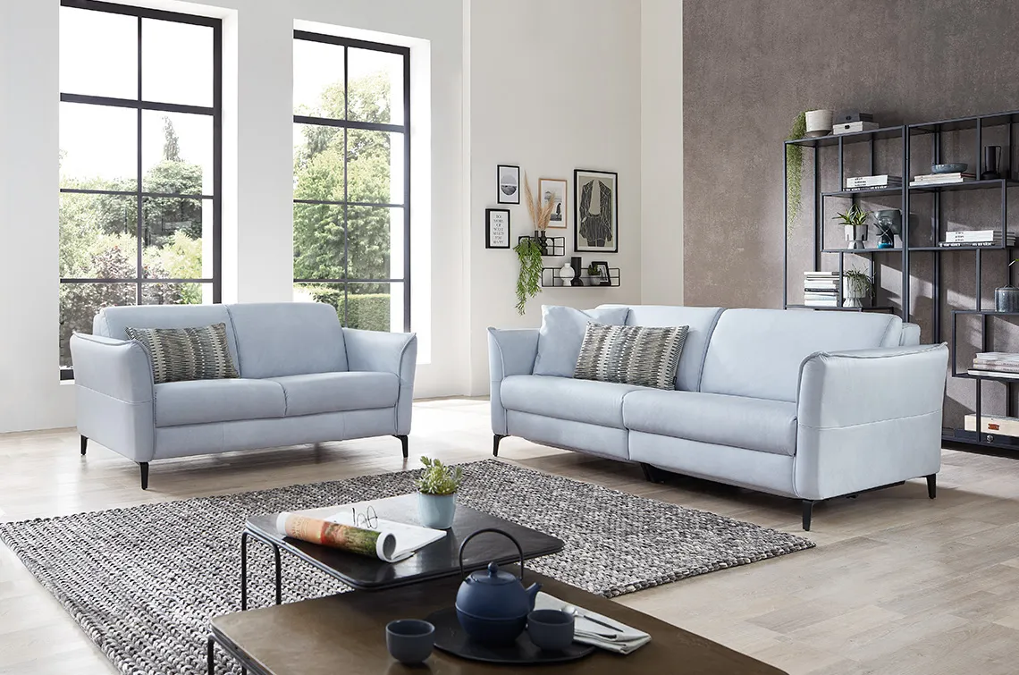 Zwei hellblaue Sofa Garnituren in einem hellen gemütlichen Raum.