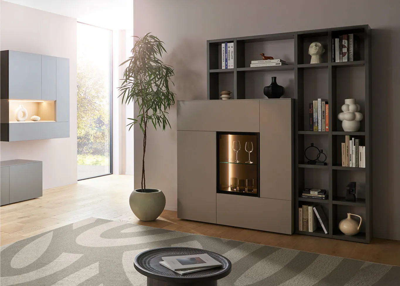 Hölzernes Highboard mit Schubladen und Vitrine neben grauem Sessel im Wohnzimmer