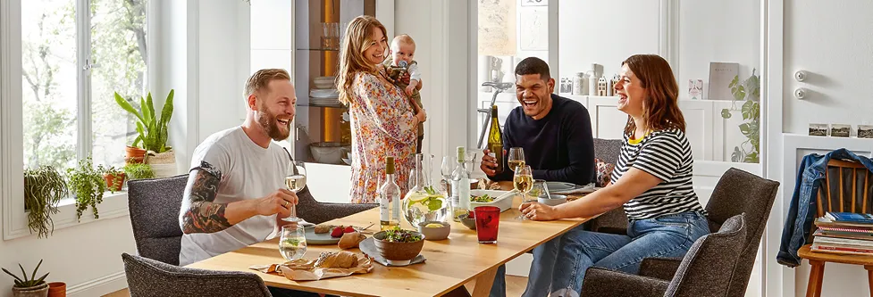 Gruppe von Freunden lachend an Esstisch im Esszimmer