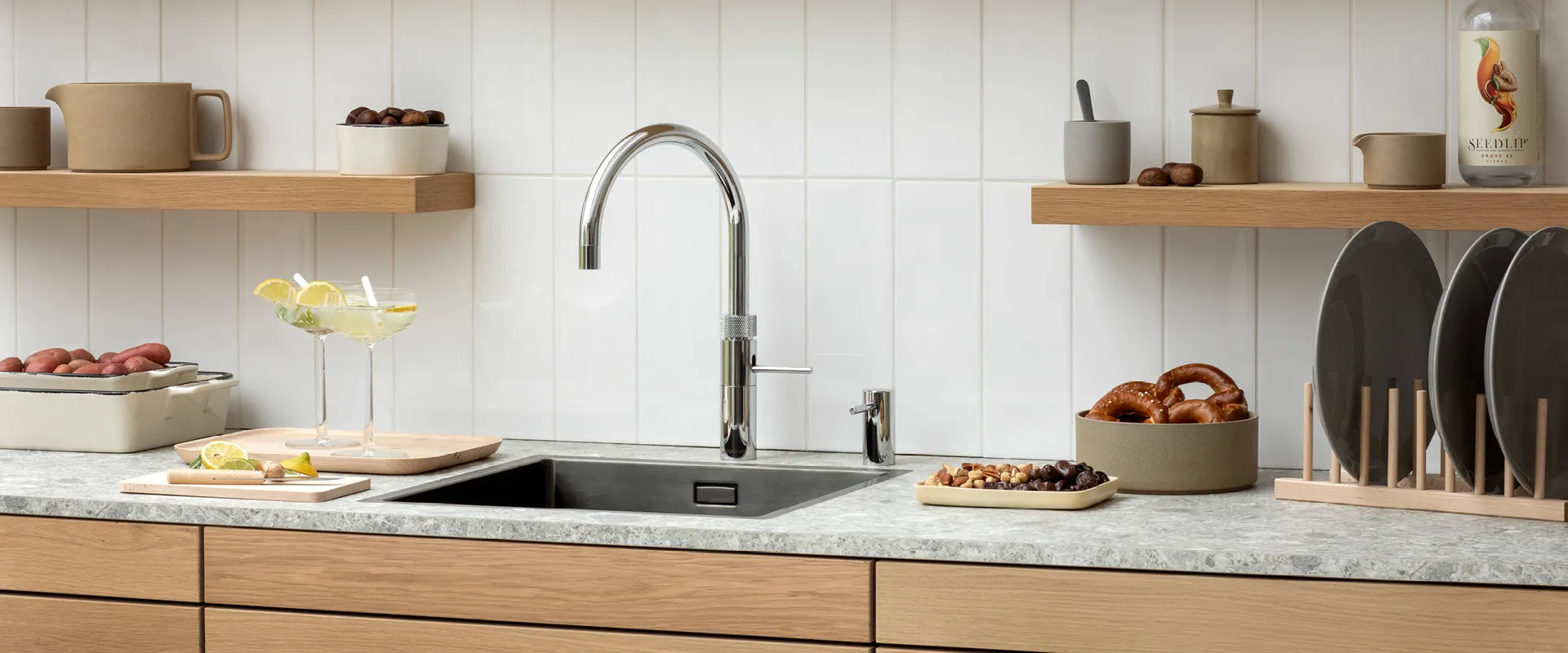 Marmor Arbeitsplatte mit Spüle und einem silbernen Wasserhahn. Moderne Küchenutensilien auf Regalbrett.