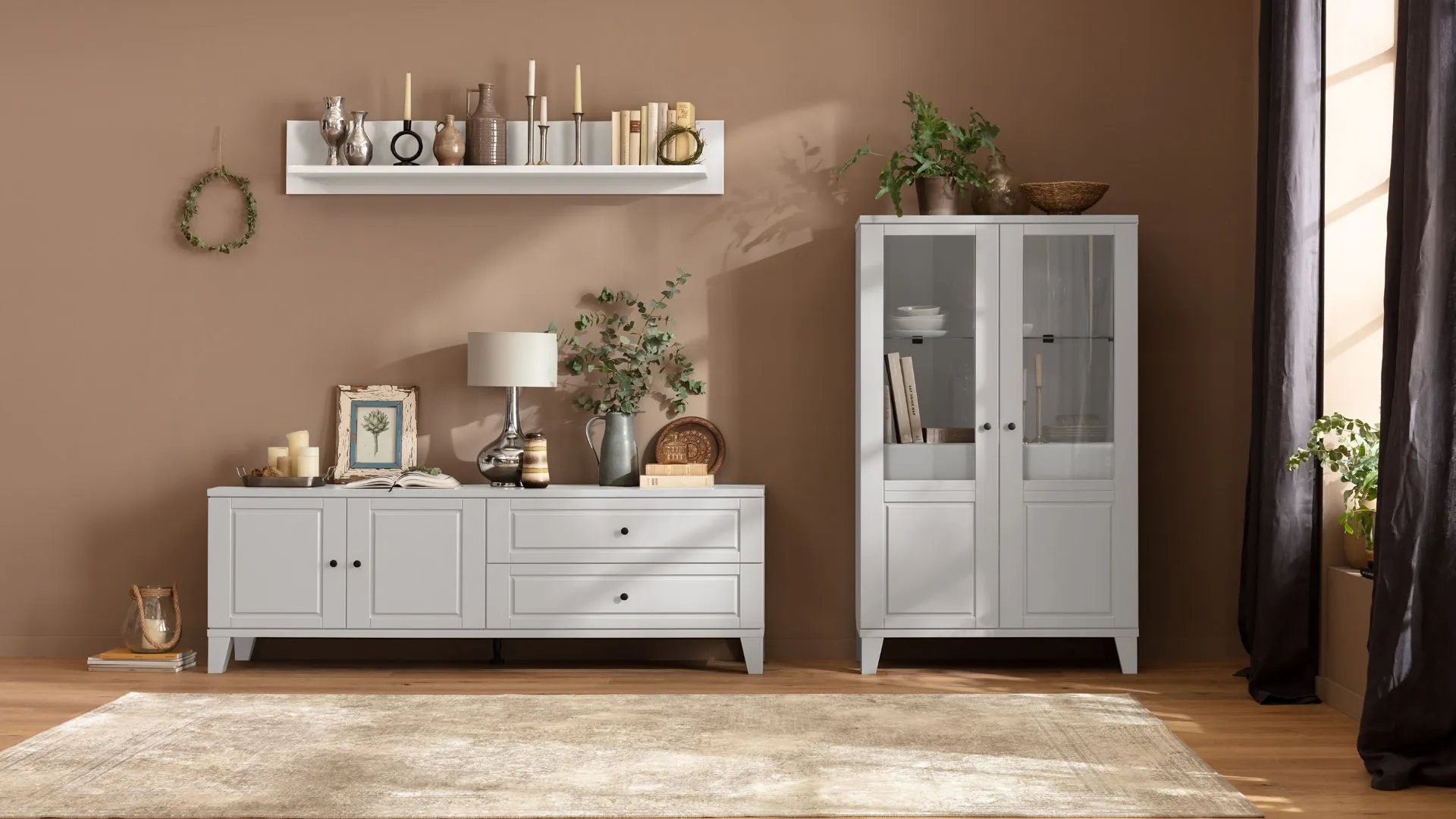  Kreidefarbene Wohnwand im Landhausstil bestehend aus einem Wandregal, Lowboard und Highboard mit vielen Vasen, Kerzenständern dekoriert.