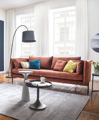 Wohnzimmer mit stylischer Couch in knackigem rot und bunten Kissen.