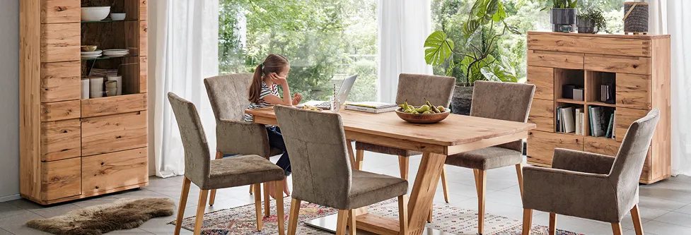 Kind mit Laptop an hoelzernem Esstisch im Esszimmer