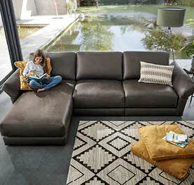 Mädchen lesend auf dunkelbraunem Ledersofa