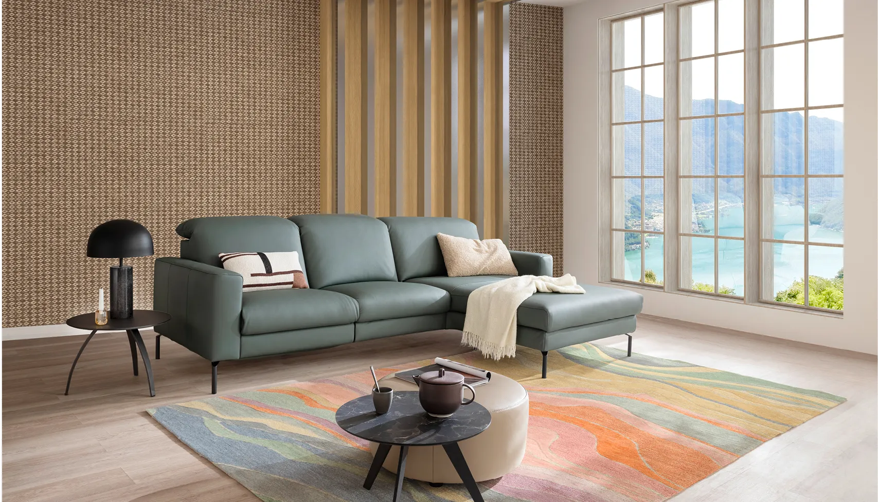 Helles Wohnzimmer mit grauem Ecksofa und Relaxsessel, dekoriert mit bunten Kissen, Pflanzen und Teppich im skandinavischen Stil – modernes Sofa-Design für gemütliches Wohnen.