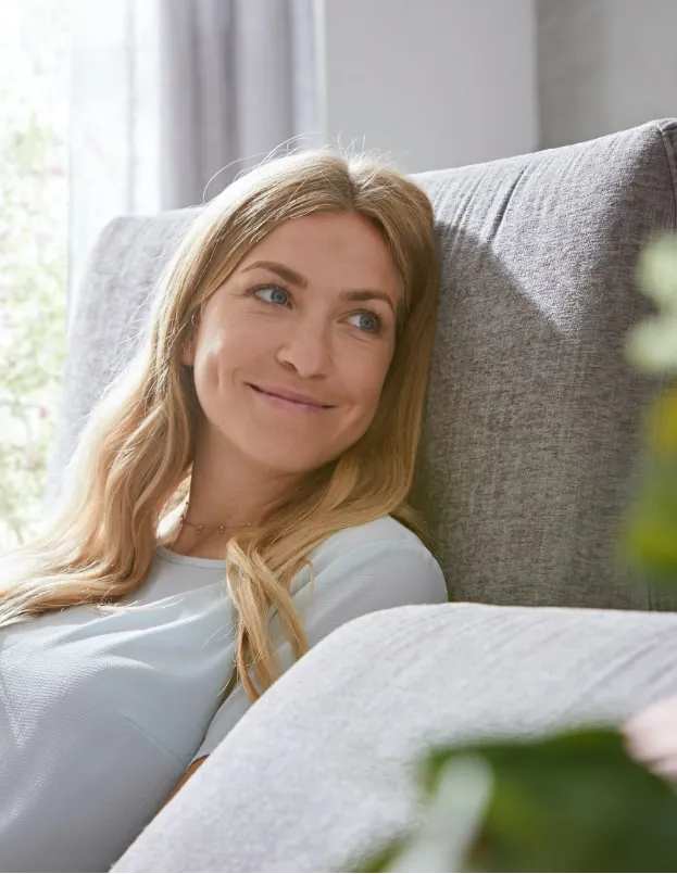 Lächelnde Frau sitzt auf grauem Sofa