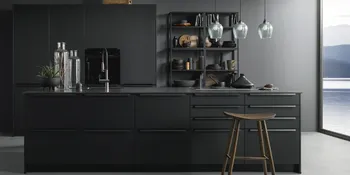 Edle Contur Inselküche mit schwarzen Fronten vor grauer Wand und großem Panoramafenster.