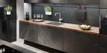 Elegante Küchenzeile mit Holzarbeitsfläche und dunkelgrauen Marmorelementen neben passender Kücheninsel.