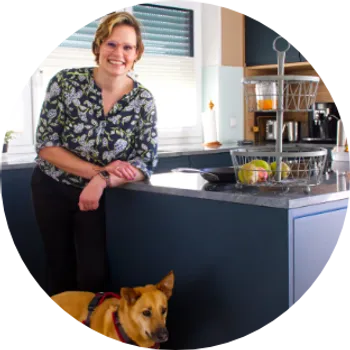 Frau in dunkelblauer Küche mit Hund