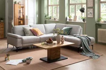 Ein Wohnzimmer mit einem grauen Ecksofa und einem Tisch.