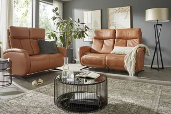 Zwei Ledersofas in Cognac mit hoher Rückenlehne.