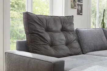 Großes schwarzes gestepptes Rückenkissen eines hellblauen Sofas.