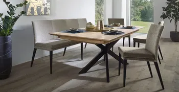 Moderne Sitzbank und Esszimmerstühle mit grauem Bezug und schwarzen Beinen um einen Esstisch aus Massivholz mit schwarzem Gestell.
