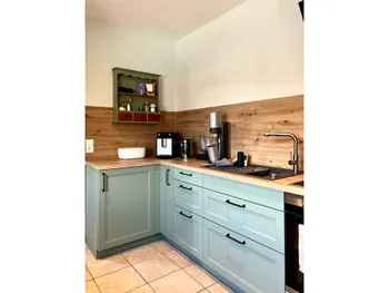 Eckküche mit grüner Front und Arbeitsplatte aus Holz