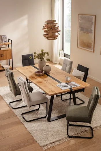 Modernes Esszimmer mit mehreren Freischwinger Esszimmerstühlen in beige, grau und grün an einem großen Esstisch aus Massivholz.
