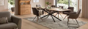 Modernes Esszimmer mit einem Massivholztisch, Schalenstühle in grau und braun vor einem großen Fenster mit vielen grünen Pflanzen.