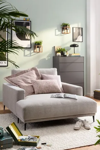 Silberfarbener Loungechair, auf dem mehrere Kissen liegen.