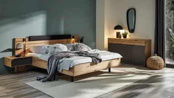 Modernes Schlafzimmer bestehend aus Bett und anhängendem Nachttisch aus Massivholz mit schwarzen Elementen und einem Sideboard mit Türen aus schwarzem Lack und Massivholz.