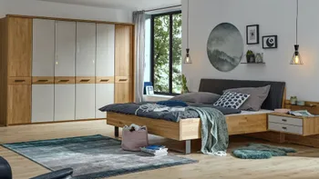 Helles Schlafzimmer mit Massivholz Bett und großem Kleiderschrank mit weißen Elementen.