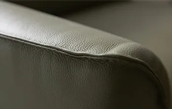 Nahaufnahme einer Sofalehne aus hochwertigem Echtleder in Olivgrün – fein genarbte Oberfläche mit eleganter Steppnaht für exklusiven Sitzkomfort und stilvolles Design.