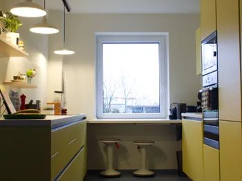 Gelbe Küche in schmalem Raum mit Sitzplatz am Fenster