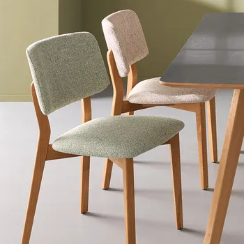 Zwei Esszimmerstühle im Skandi Look nebeneinander mit naturfarbenem und grünem Bezug.