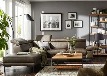 Bodenfreies grünes Leder Ecksofa mit klappbaren Kopfstützen in einem hellen Raum.