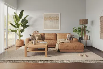 Ledersofa in der Farbe Cognac in einem modernen Wohnzimmer mit Pflanzen dekoriert und einer großen Standlampe.