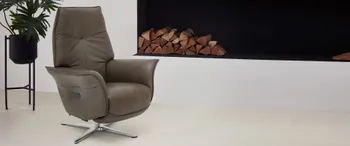 Brauner Leder Relaxsessel mit silbernem Sternfuß neben einem Kamin.