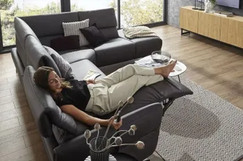 Eine Frau liegt entspannt auf einem schwarzen Ledersofa in Relaxposition.