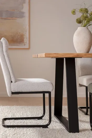 Weißer Freischwinger mit schwarzem Metallgestell, der an einem Massivholztisch steht.