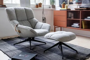 Grauer Sessel mit passendem Hocker. 