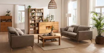 Gemütliches Wohnzimmer mit vielen Pflanzen und Vasen, in dem sich zwei graue Ledersofas gegenüber stehen, dazwischen steht ein eckiger Couchtisch aus Massivholz.