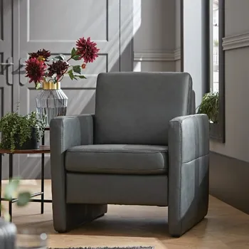 Grauer Sessel mit Lederbezug, neben einem Beistelltisch mit Blumenvase und roten Blumen.