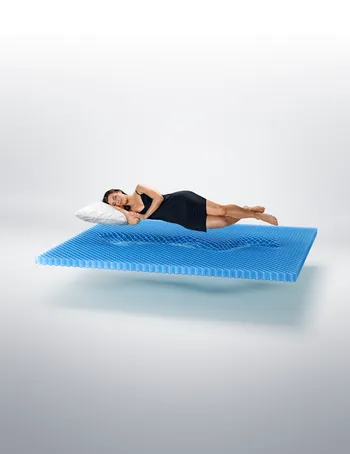 Eine Frau schläft entspannt auf einer schwebenden IntelliGel®-Matratze von Svane®. Die Struktur der Matratze passt sich perfekt an ihren Körper an und bietet ergonomische Unterstützung für höchsten Schlafkomfort.