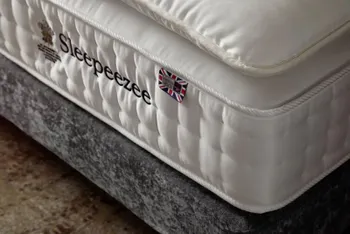 Boxspringbett mit grauem Rahmen mit Stoffbezug, auf dem eine Sleepeezee Matratze liegt und darüber ein Topper.